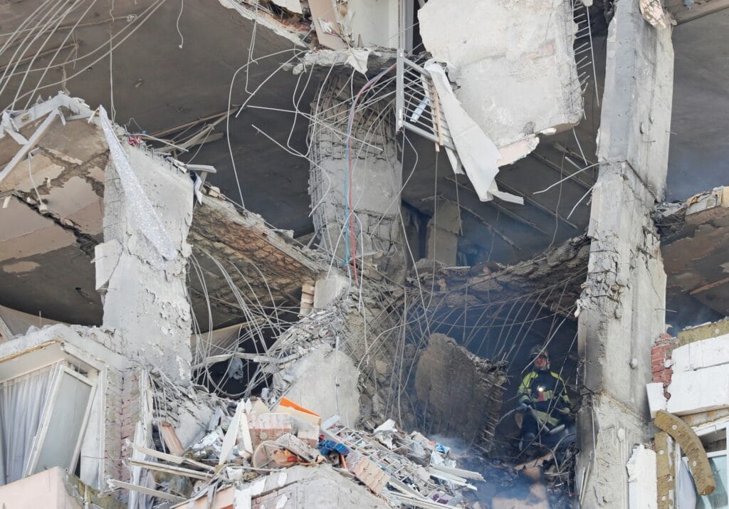 Hasič zasahuje uvnitř poškozeného domu v Kyjevě