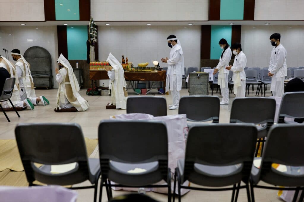 Rodinní příslušníci oběti covidu-19 se modlí během pohřbu
