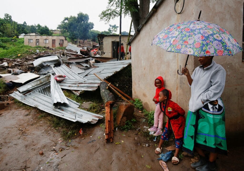 Lidé stojí poblíž trosek budovy, která byla zničena během záplav