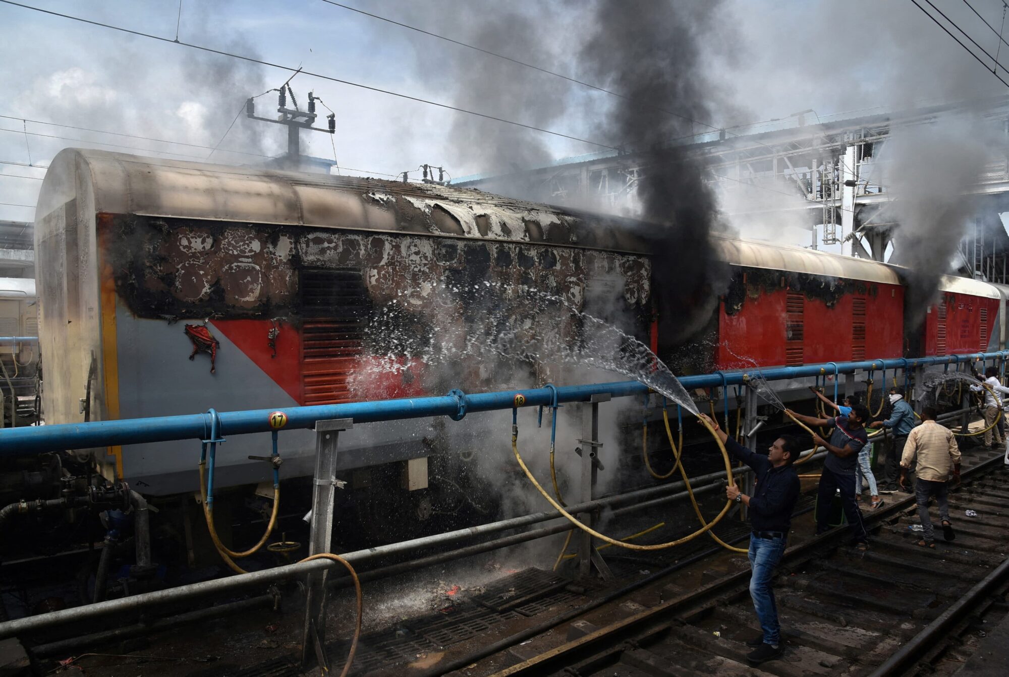 Zaměstnanci železnice hasí jeden ze zapálených vlaků 