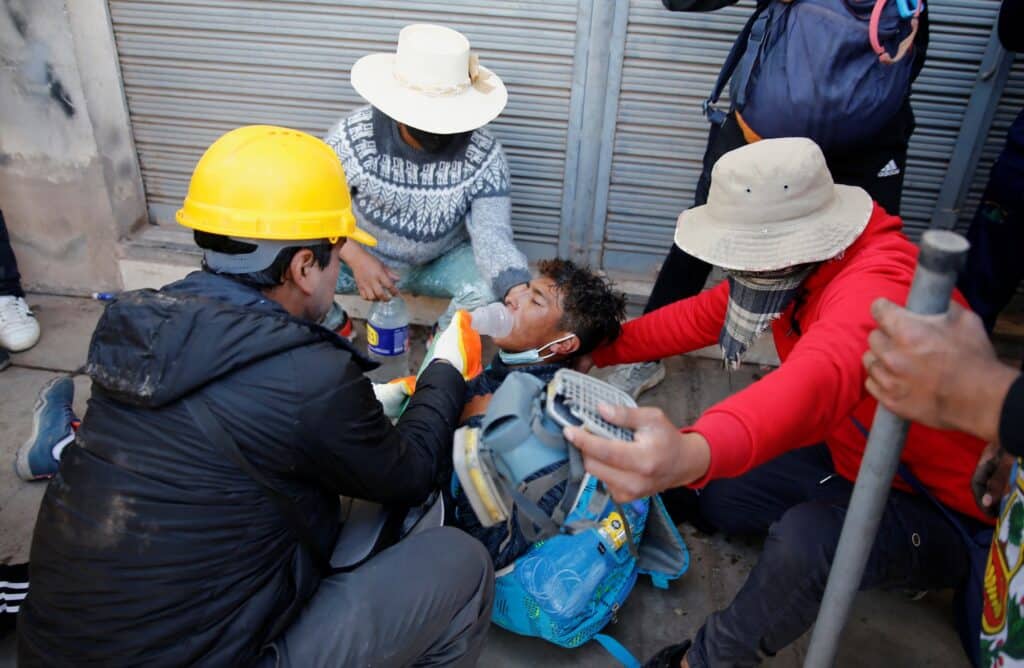 Demonstranti pomáhají zraněnému muži během střetu s bezpečnostními silami