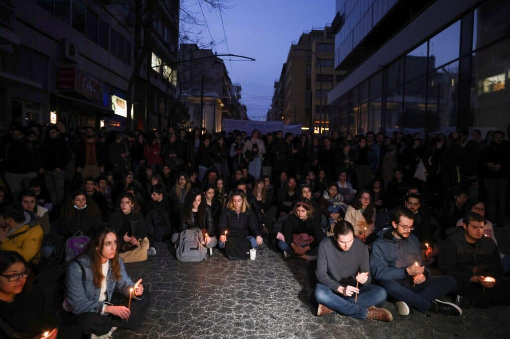 Demonstranti drží svíčky během demonstrace před centrálou Hellenic Train