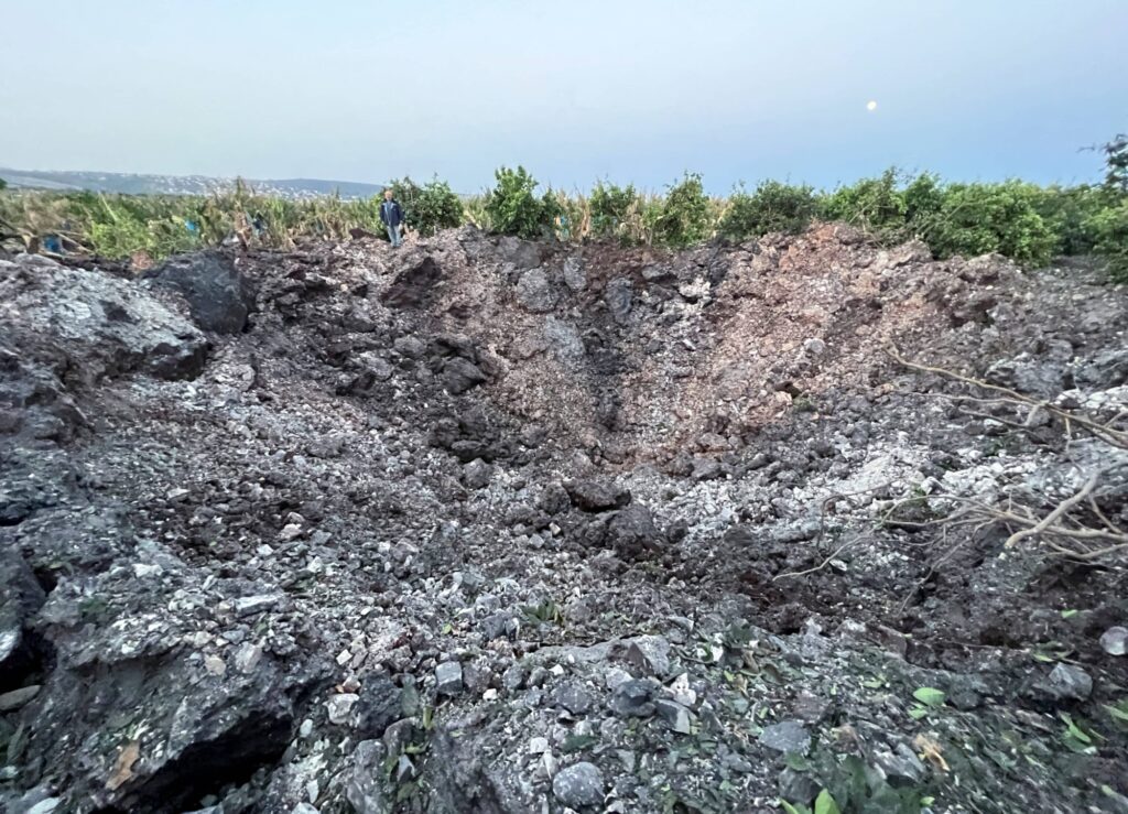 Muž stojí u kráteru po dopadu rakety v Libanonu 