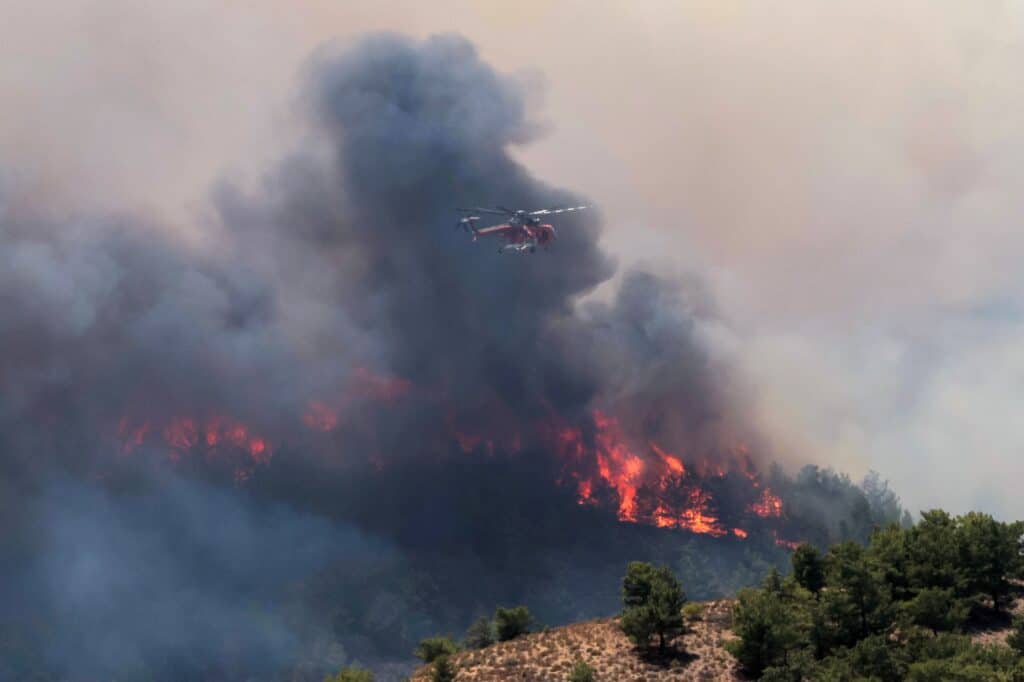 Hasičský vrtulník se připravuje na shoz vody při požáru u vesnice Archangelos